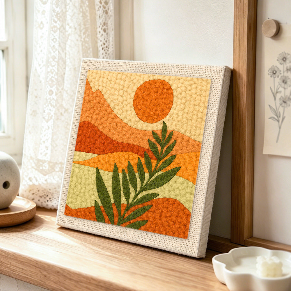 Minimalist leaf and mountain scenery punch needle artwork displayed on a table