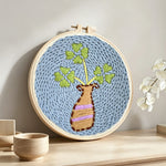 Minimalist vase and leaves punch needle artwork displayed on a table