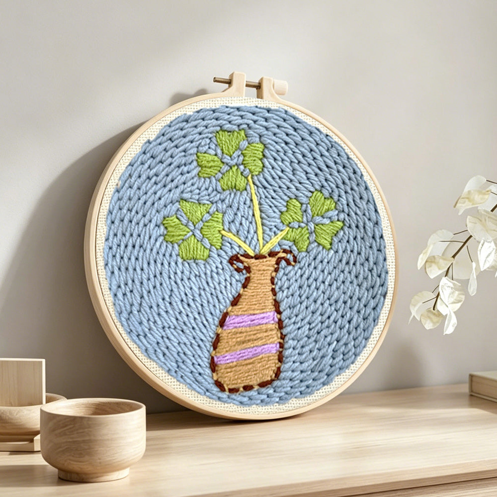 Minimalist vase and leaves punch needle artwork displayed on a table