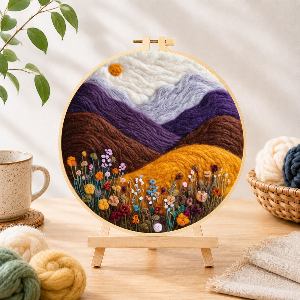 Finished misty purple mountains and wildflowers needle felting displayed on a wooden easel