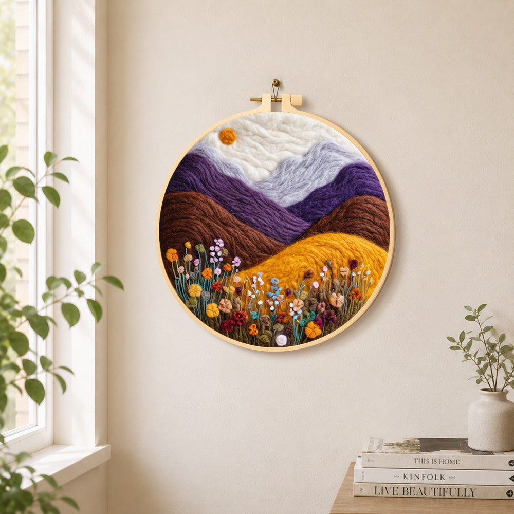 Misty purple mountains and wildflowers needle felt wall art displayed in a bright home interior