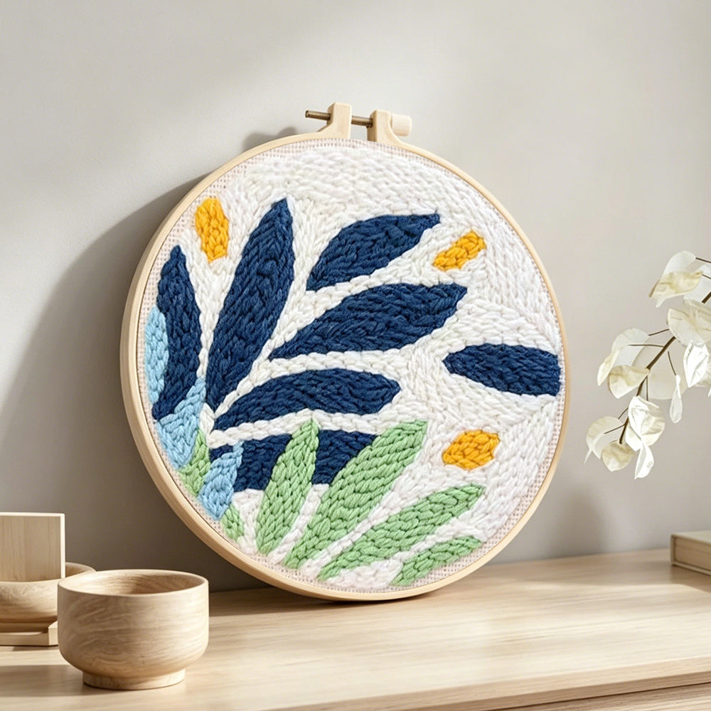 Modern blue and green leaves punch needle artwork displayed on a table
