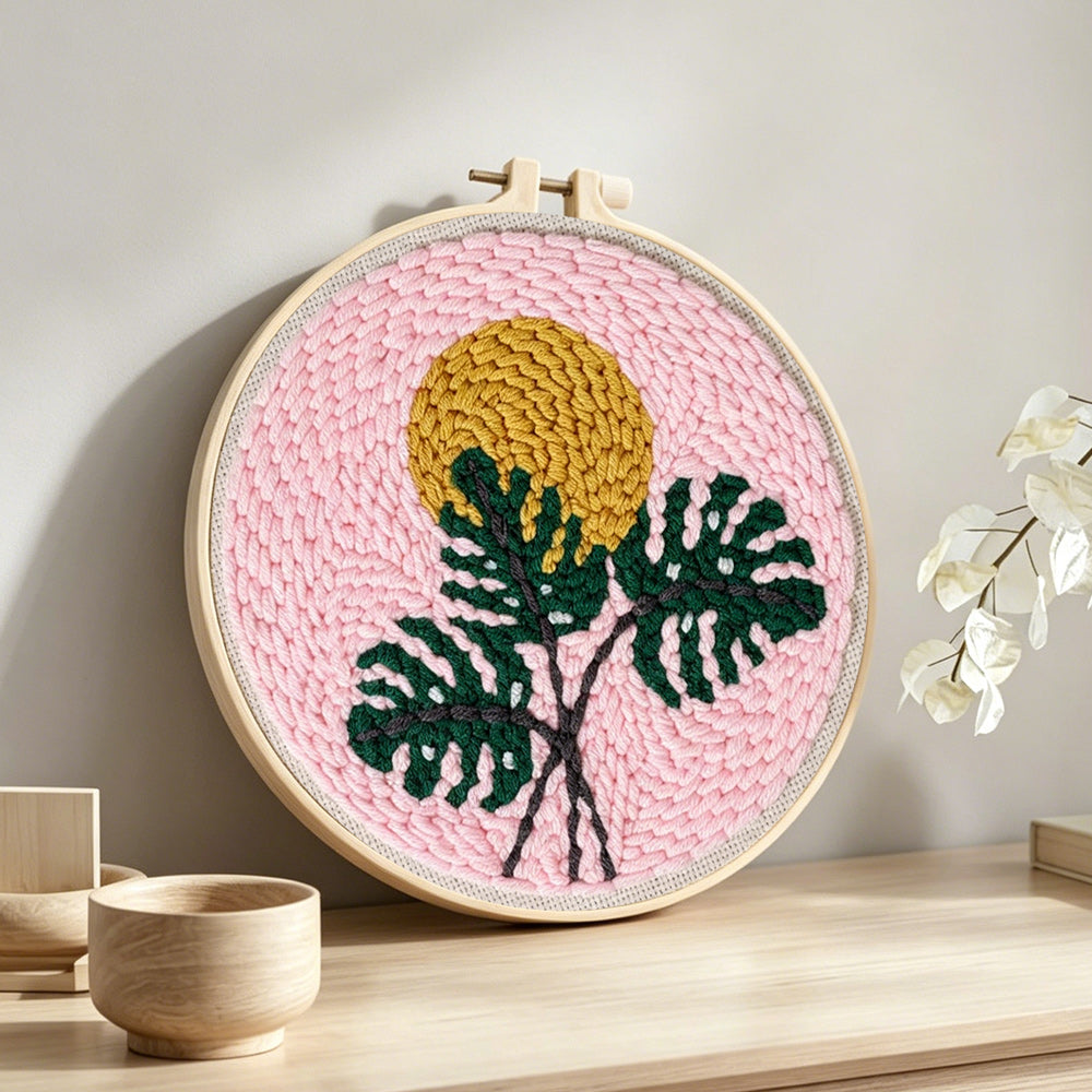 Monstera leaf and golden sun punch needle artwork displayed on a table