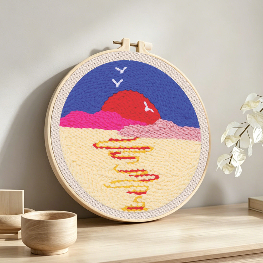 Moon over sea with birds at sunset punch needle artwork displayed on a table