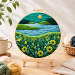 Finished moonlit river scene with bright flowers needle felting displayed on a wooden easel