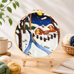 Finished moonlit snowy cabin with warm glow needle felting displayed on a wooden easel