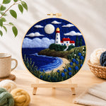Finished moonlit white lighthouse and blue roses needle felting displayed on a wooden easel