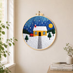 Moonlit yellow house and red bushes needle felt wall art displayed in a bright home interior