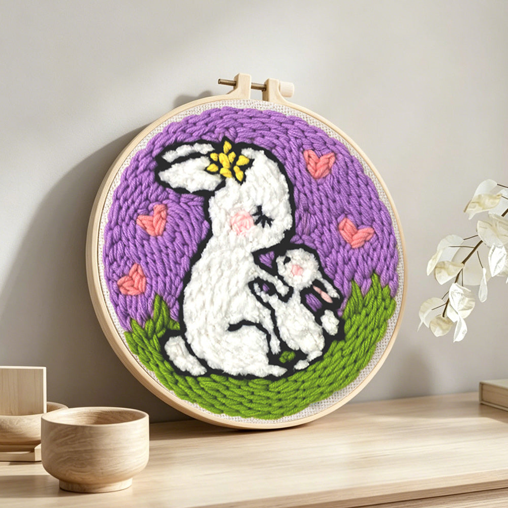 Mother rabbit carrying baby bunny punch needle artwork displayed on a table
