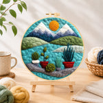 Finished mountain and potted plants needle felting displayed on a wooden easel