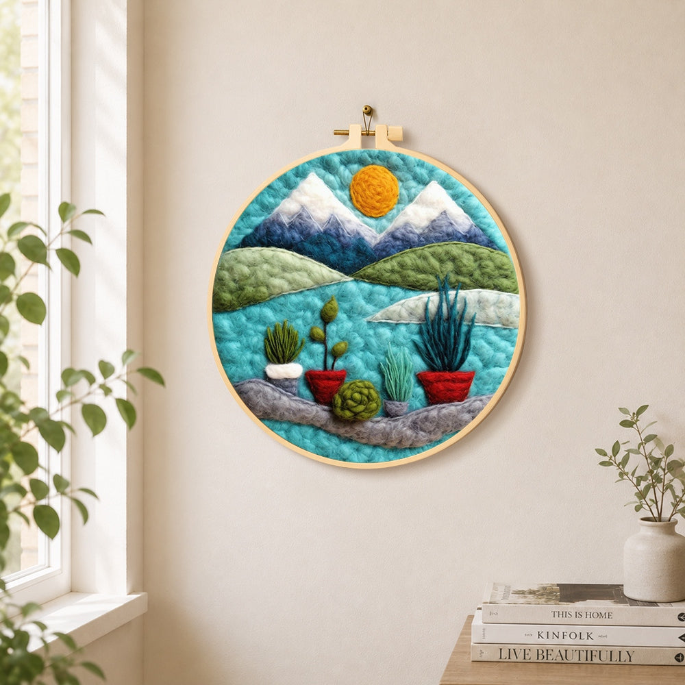 Mountain and potted plants needle felt wall art displayed in a bright home interior