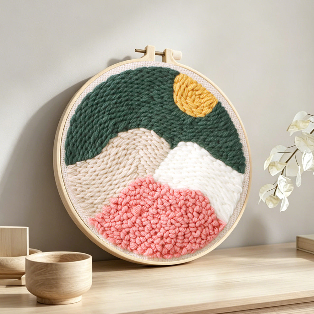 Mountain landscape with sun punch needle artwork displayed on a table