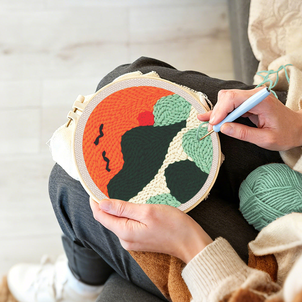 Creating handmade mountains with flying birds at sunset punch needle artwork