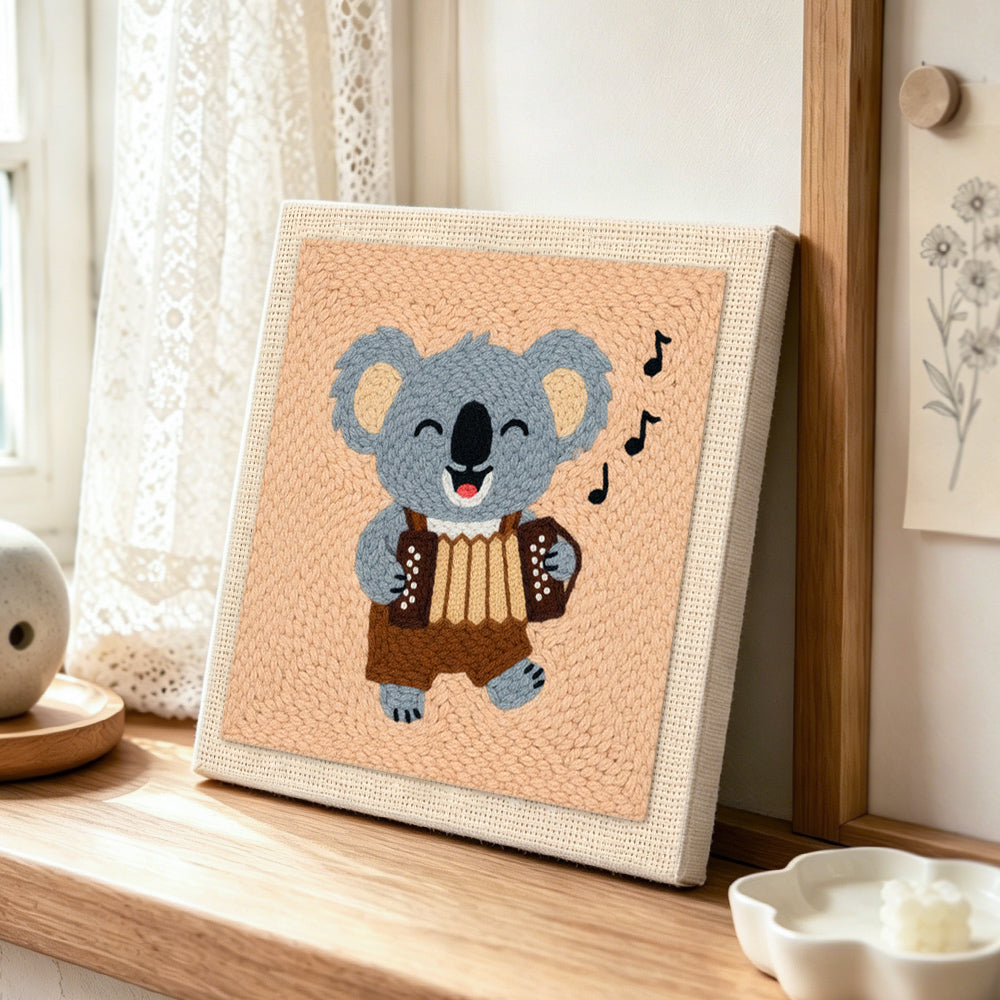 Musical koala playing accordion punch needle artwork displayed on a table