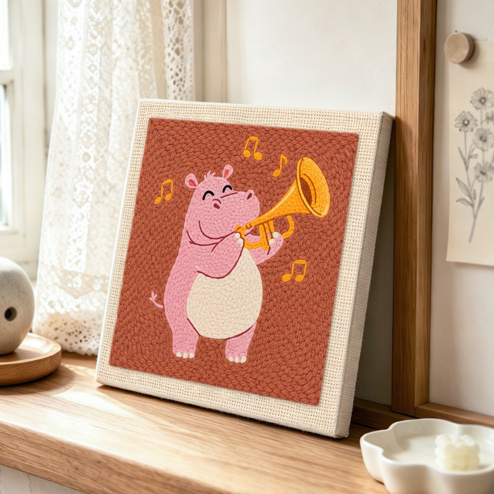 Musical pink hippo with trumpet punch needle artwork displayed on a table
