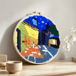 Night scene with yellow-lit buildings punch needle artwork displayed on a table