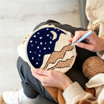 Creating handmade night sky with moon, stars and beige sand dunes punch needle artwork