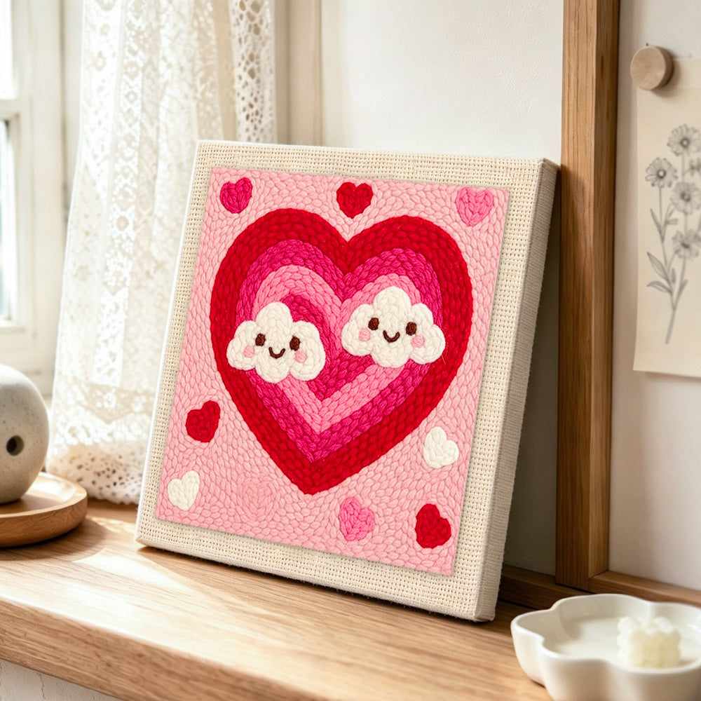 Ombre heart with kawaii clouds punch needle artwork displayed on a table