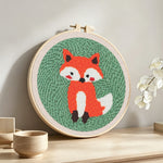 Orange baby fox punch needle artwork displayed on a table