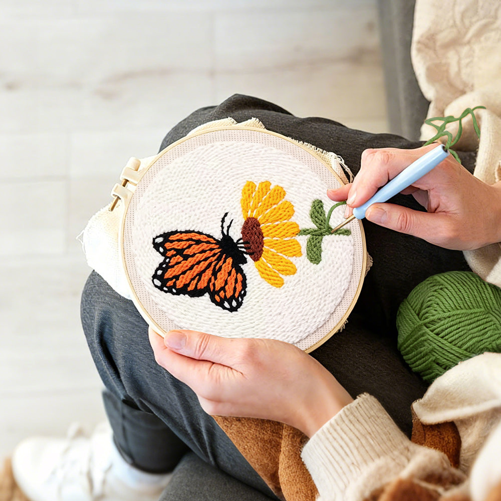 Creating handmade orange butterfly resting on flower punch needle artwork