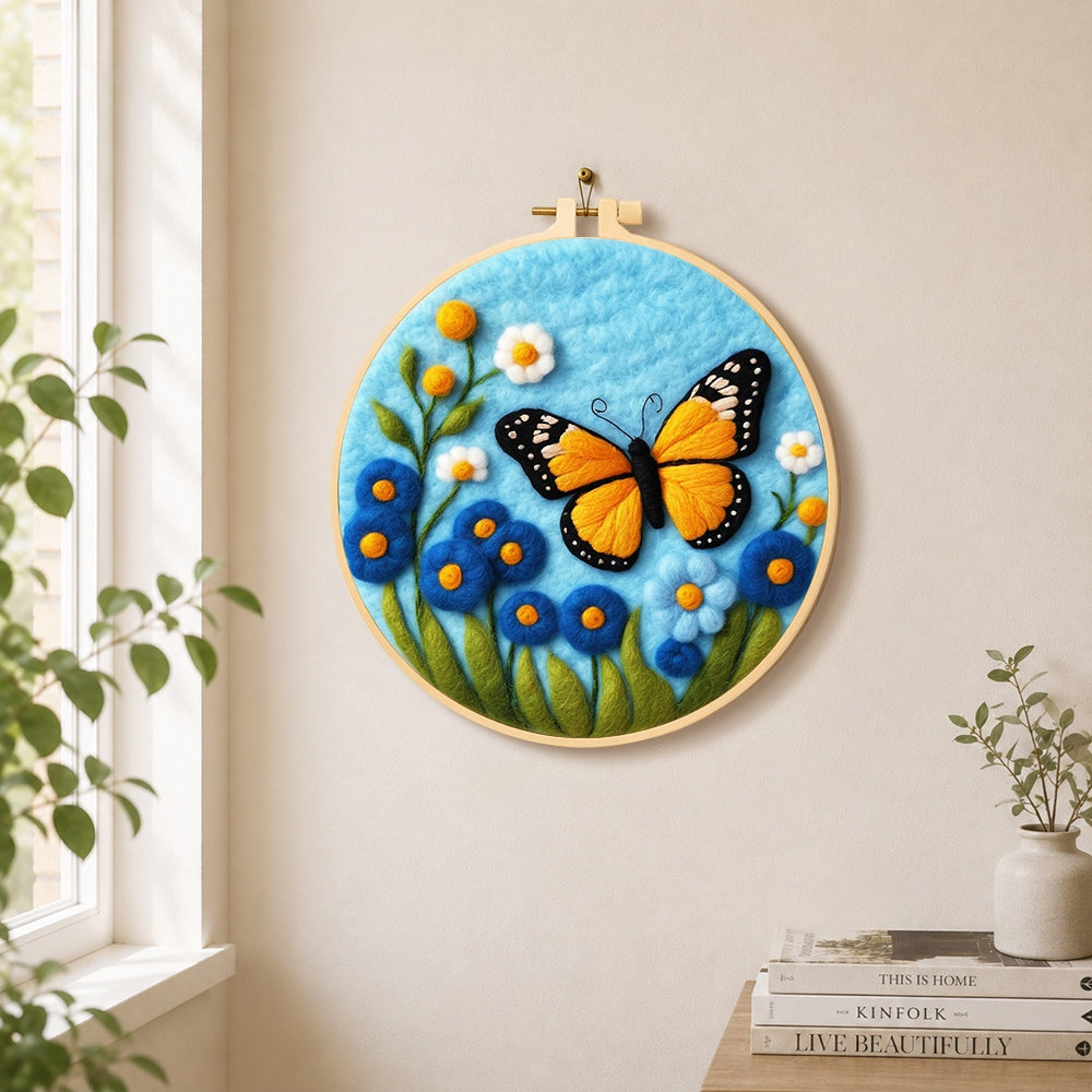 Orange monarch butterfly and blue flowers needle felt wall art displayed in a bright home interior