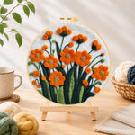 Finished orange-red flower cluster needle felting displayed on a wooden easel