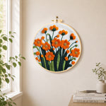 Orange-red flower cluster needle felt wall art displayed in a bright home interior