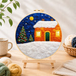Finished orange snowy house and christmas trees needle felting displayed on a wooden easel