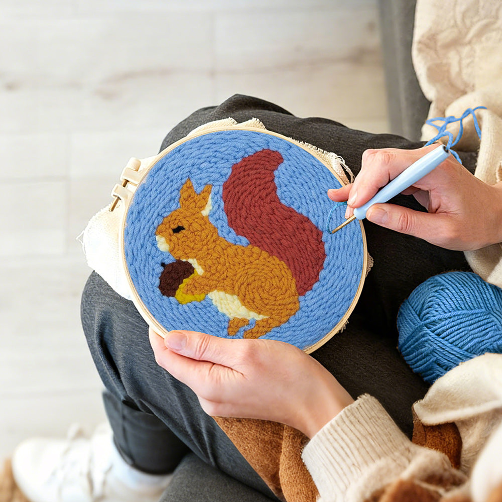 Creating handmade orange squirrel holding pine cone punch needle artwork