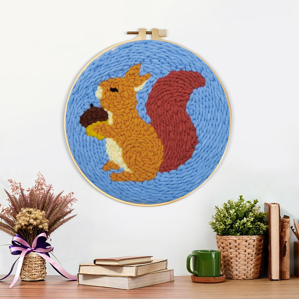Finished orange squirrel holding pine cone artwork displayed on a wall