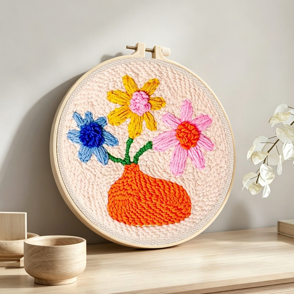 Orange vase with colourful flowers punch needle artwork displayed on a table