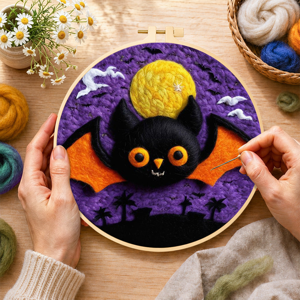 Creating the orange-winged bat under the purple night wool painting by hand with a felting needle