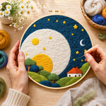 Creating the oversized moon over red-roof cottage wool painting by hand with a felting needle