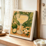 Pale yellow cocktail with lime punch needle artwork displayed on a table