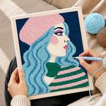 Creating handmade pastel blue haired woman in pink beret punch needle artwork