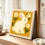 Peaceful white bunny with daisies punch needle artwork displayed on a table