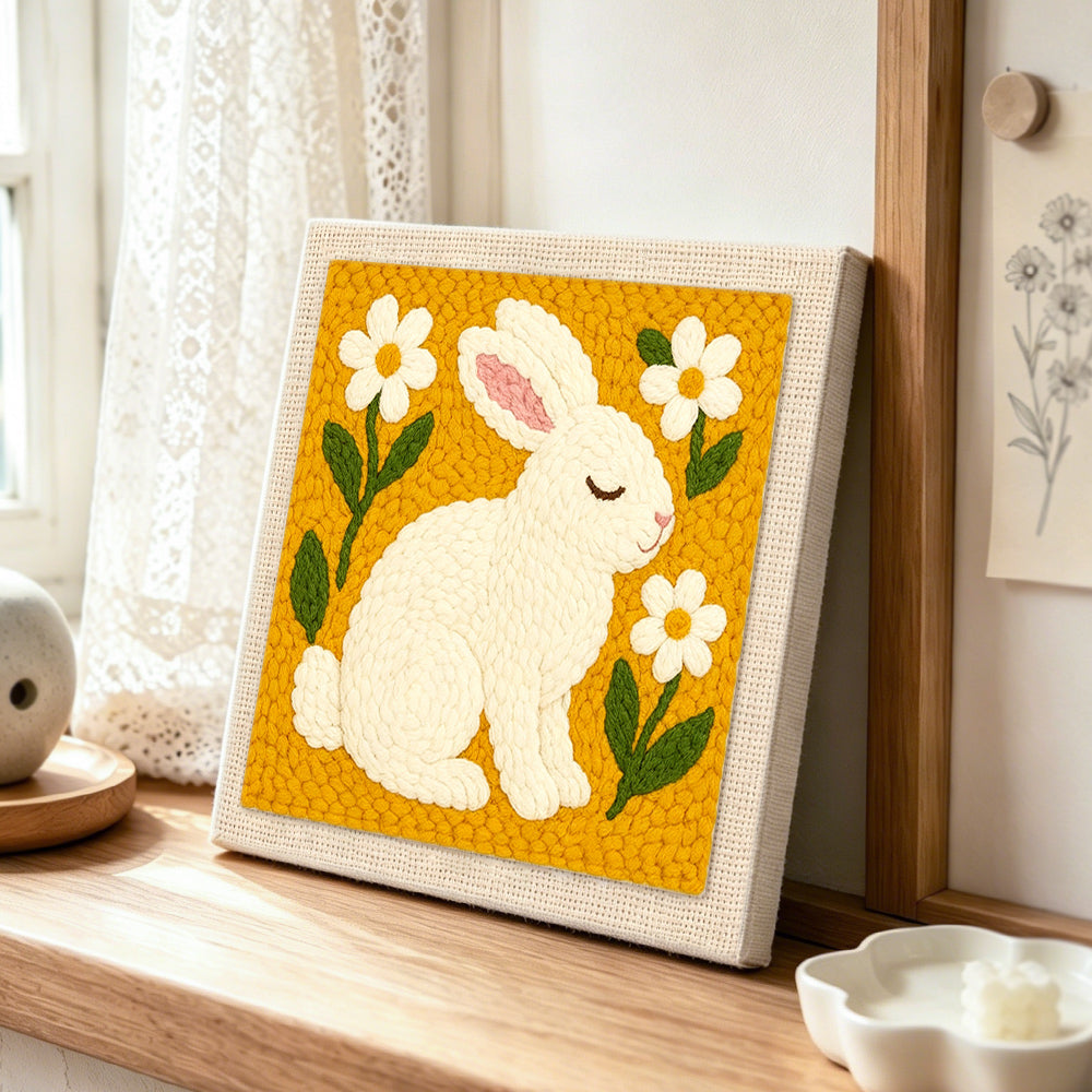 Peaceful white bunny with daisies punch needle artwork displayed on a table