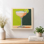Finished peach drink with lime garnish artwork displayed on a wall