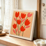Peach tulips punch needle artwork displayed on a table