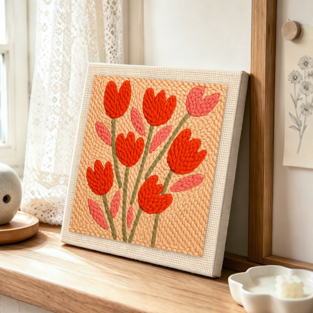 Peach tulips punch needle artwork displayed on a table