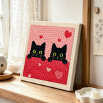 Peeking black cat duo with green eyes punch needle artwork displayed on a table