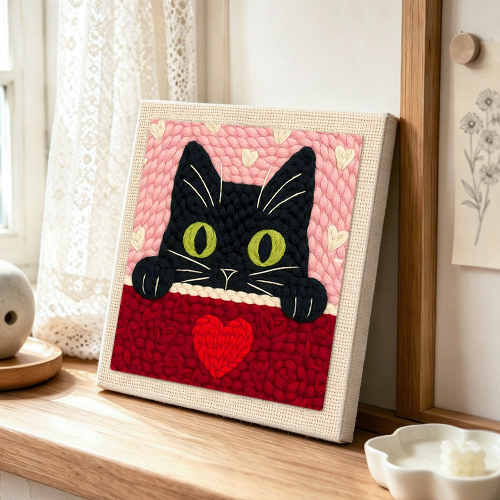 Peeking black cat with green eyes punch needle artwork displayed on a table