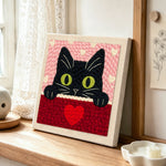 Peeking black cat with green eyes punch needle artwork displayed on a table