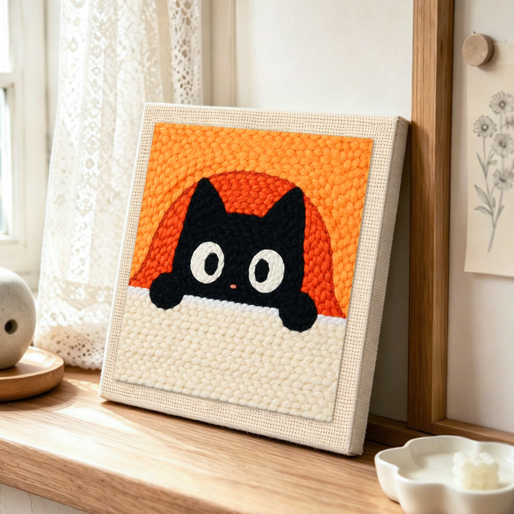 Peeking black cat with orange arch background punch needle artwork displayed on a table