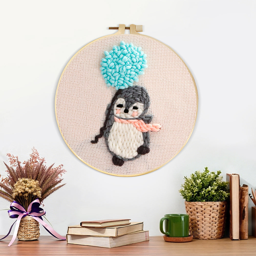 Finished penguin with blue balloon pom artwork displayed on a wall