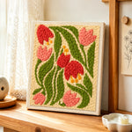 Pink and red bell flowers punch needle artwork displayed on a table