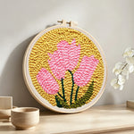 Pink blooms on mustard yellow background punch needle artwork displayed on a table