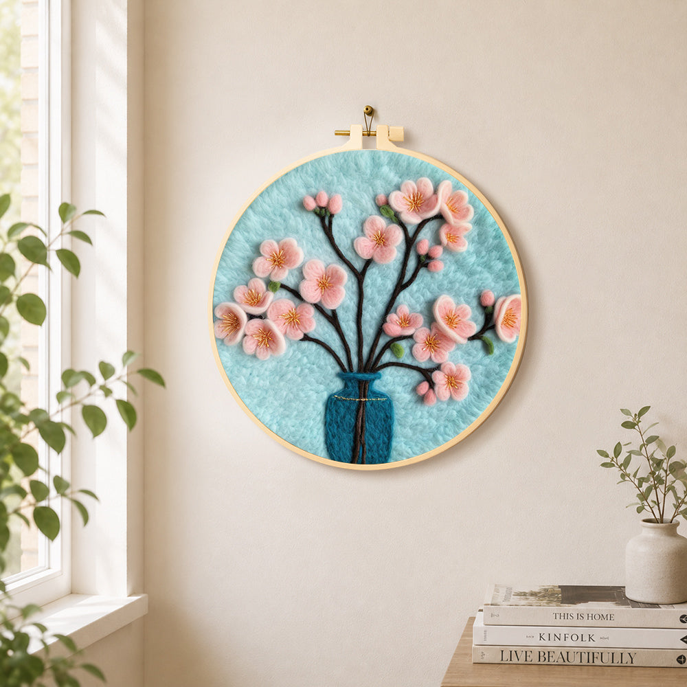 Pink blossom in blue vase needle felt wall art displayed in a bright home interior