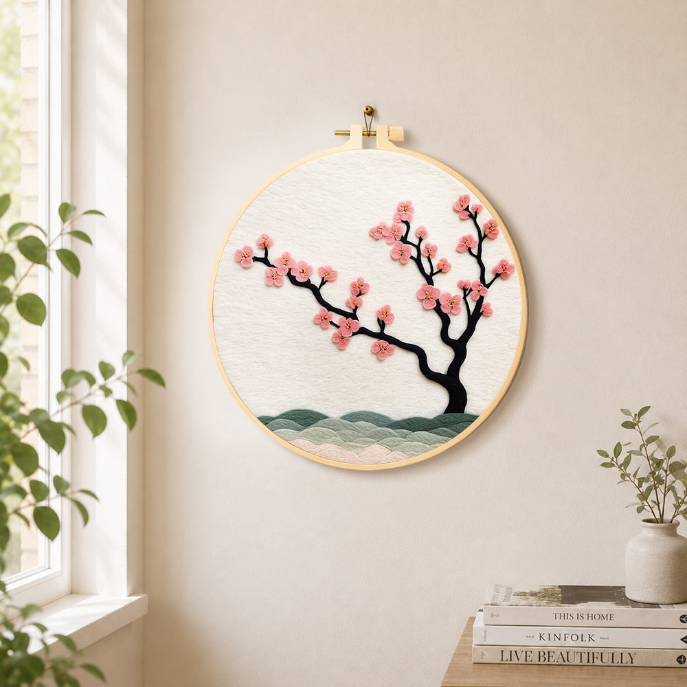 Pink blossom on black branch needle felt wall art displayed in a bright home interior