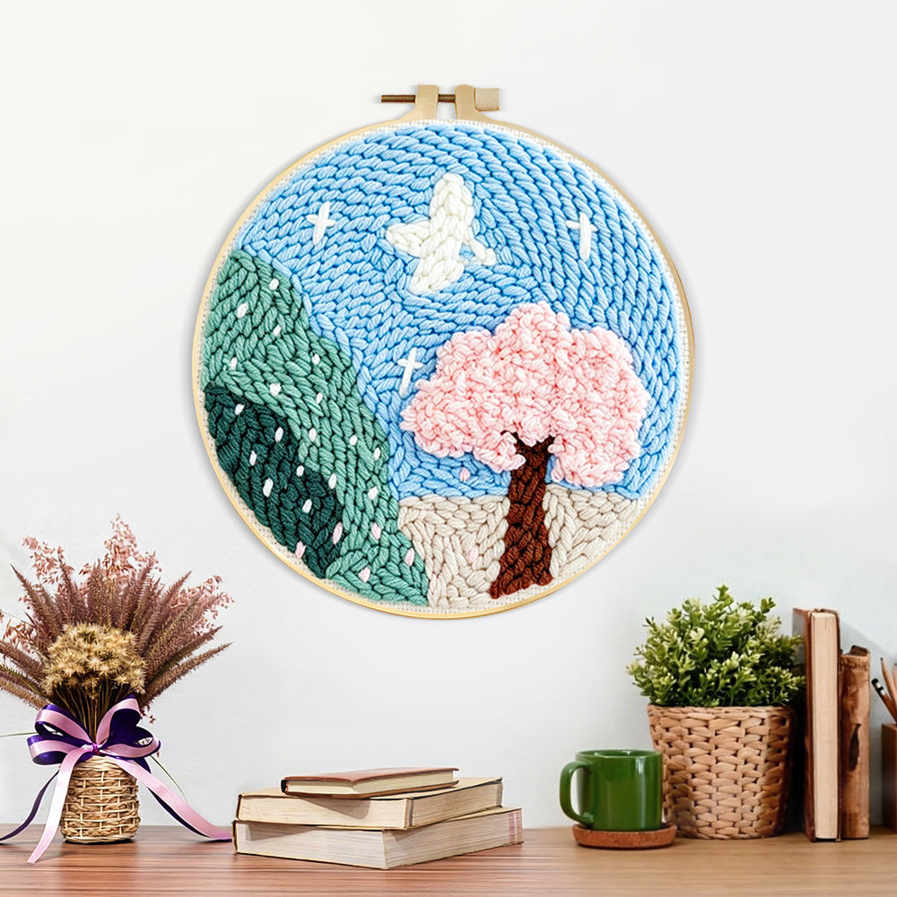 Finished pink blossom tree and green mountains artwork displayed on a wall